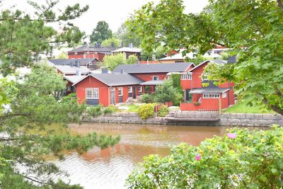 Houses by lake and buildings against trees