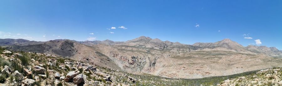 Panoramic view of landscape and mountains against blue sky