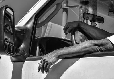 Cropped hand of man holding cigarette while driving vehicle