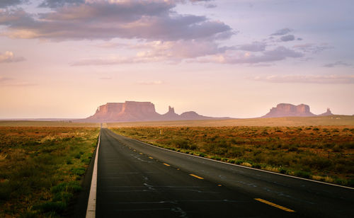 Road leading towards mountains against sky