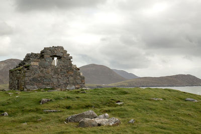 View of old ruin on field against cloudy sky