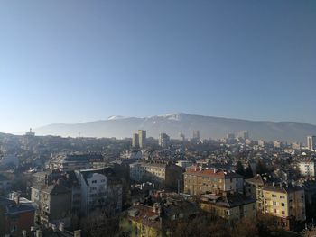 High angle view of city buildings against clear blue sky