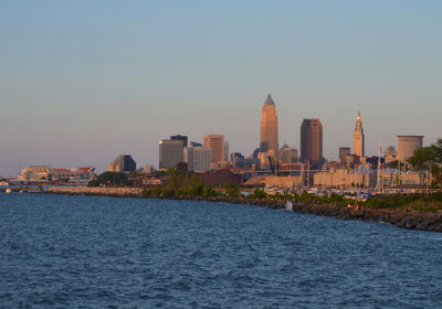 Sea by buildings against clear sky in city