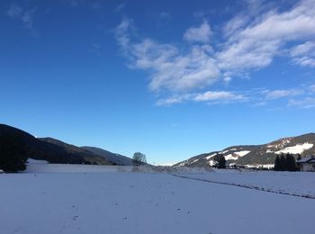 Scenic view of landscape against blue sky during winter