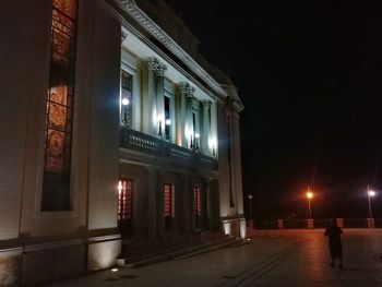 Illuminated street amidst buildings in city at night