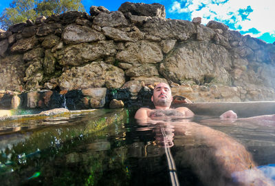 Portrait of shirtless man lying in hot spring