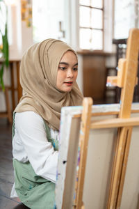 Rear view of woman using laptop at home