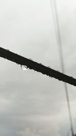 Low angle view of raindrops on metal against sky