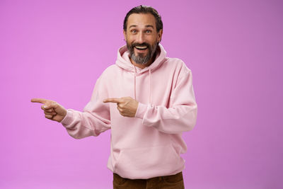 Portrait of happy man standing against pink background