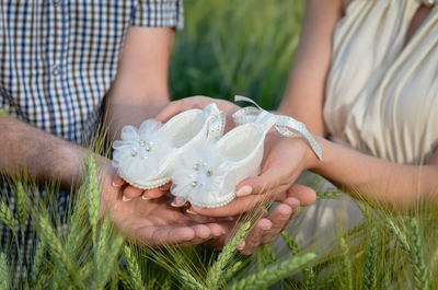 Midsection of people holding white flowering plants