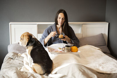 Young woman with dog sitting on bed