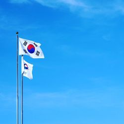 Low angle view of flag against blue sky