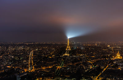 Distant view of eiffel tower amidst illuminated cityscape against sky at night