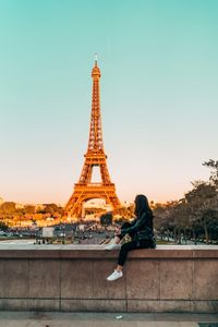 Woman sitting against eiffel tower in city