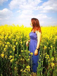 Woman standing on field with yellow flowers in background