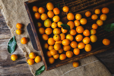 Overhead view of kumquat in wooden container at table