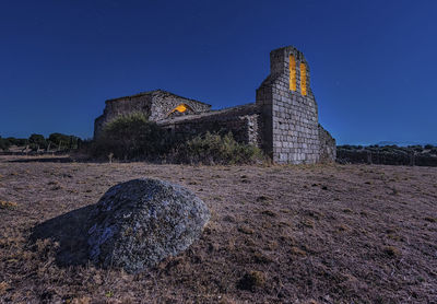 Low angle view of old building on field against clear blue sky