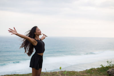 Woman standing on beach against sky