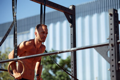 Low angle view of young man exercising in playground