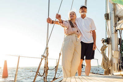 Full length of couple sitting on boat sailing in sea