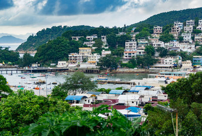 River amidst buildings and trees against cloudy sky