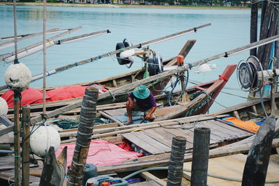 Fisherman on boat moored at lake