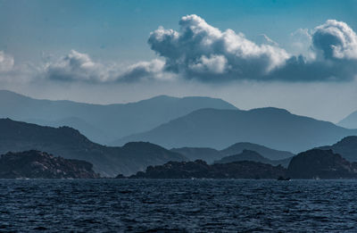 Scenic view of sea by mountains against sky