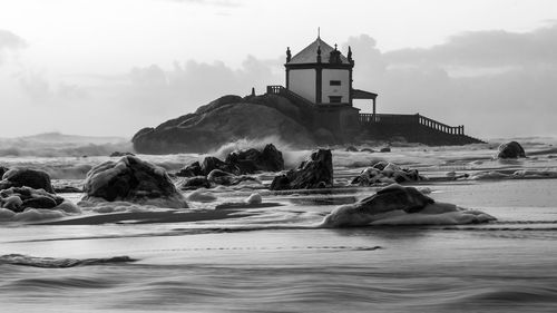 Built structure on beach by sea against sky