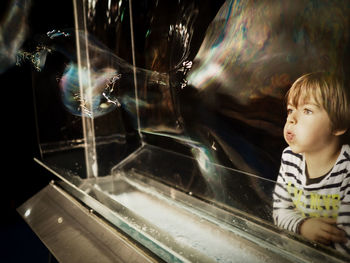 Boy playing with bubbles standing at railing