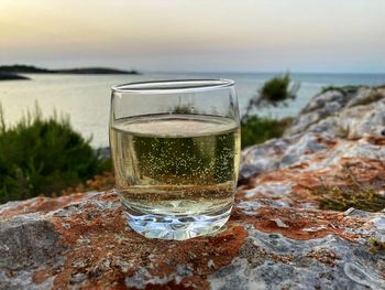 Glass of water on rock at beach against sky in gargano, italy