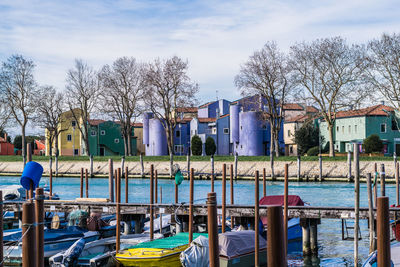 Boats moored in canal by house against sky