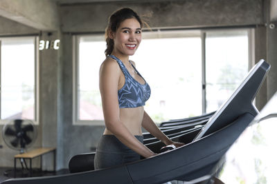 Portrait of smiling woman exercising on treadmill at gym