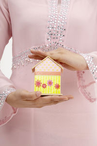 Midsection of woman holding model home against white background