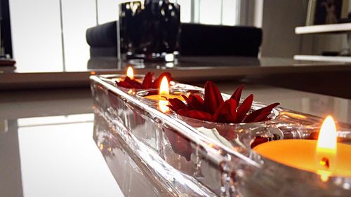 Close-up of lit tea light candles on table at home