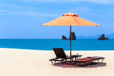 Deck chairs on beach against sky