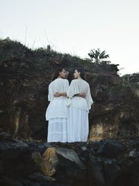 Rear view of lesbian couple standing against rock formation on field