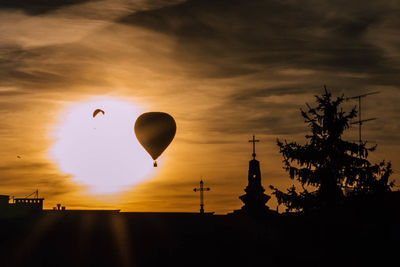 Silhouette of hot air balloon against orange sky