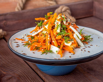 Vitamin salad of grated carrots with cheese and dill, served on a light plate