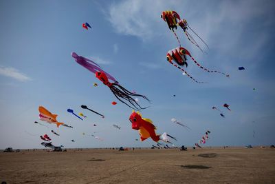 Low angle view of kites flying against sky