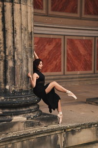 Full length portrait of young woman dancing on building