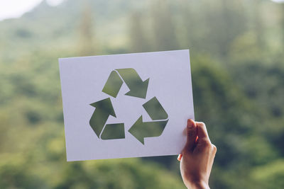 Cropped image of hand holding paper against blurred background