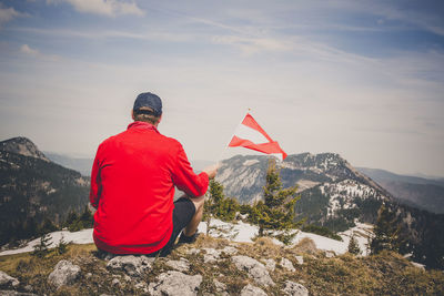 Rear view of man on rock against sky