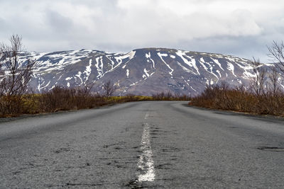 Road leading towards snowcapped mountain against sky