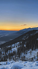 Scenic view of snow covered landscape against sky during sunset