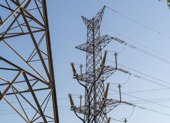 Low angle view of electricity pylon against clear sky