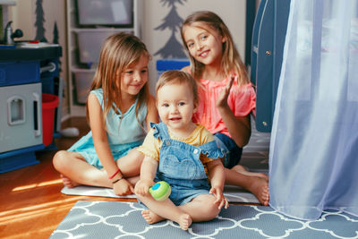 Portrait of smiling girls sitting on floor at home