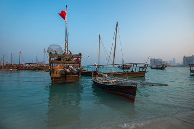 Sailboats moored on sea against clear sky