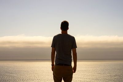 Rear view of man looking at sea against sky