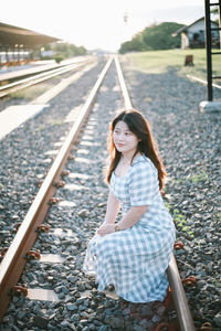 Rear view of young woman sitting on railroad track