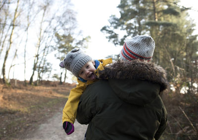 Rear view of father carrying daughter while walking on road